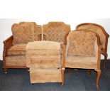 A pair of upholstered bergere armchairs and matching foot stools, together with a pair of similar