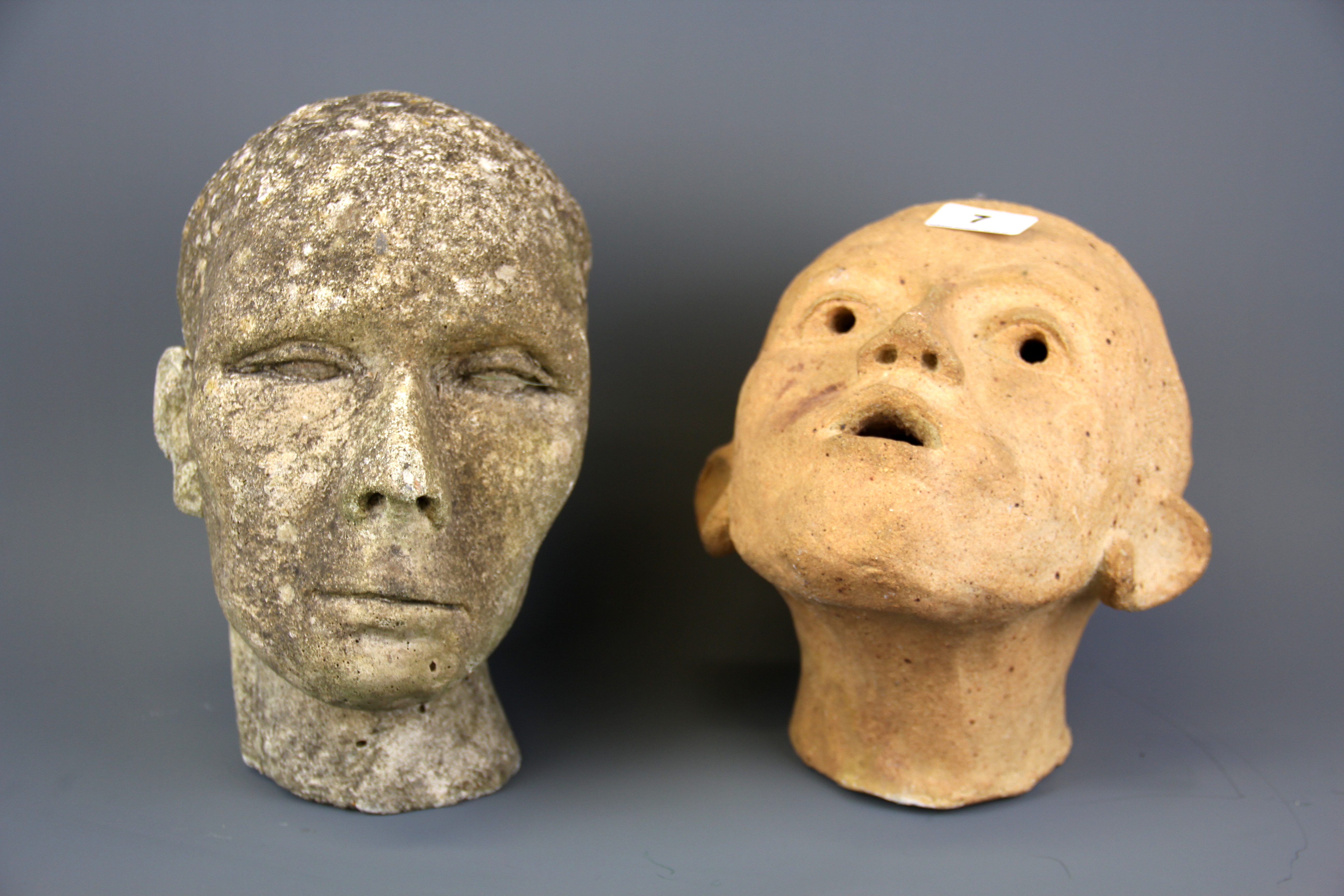 A studio pottery terracotta head, H. 23cm, together with a further concrete head, H. 26cm.