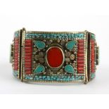 A Tibetan traditional white metal bangle decorated with enamelled mosaic, blue stones and cornelian,