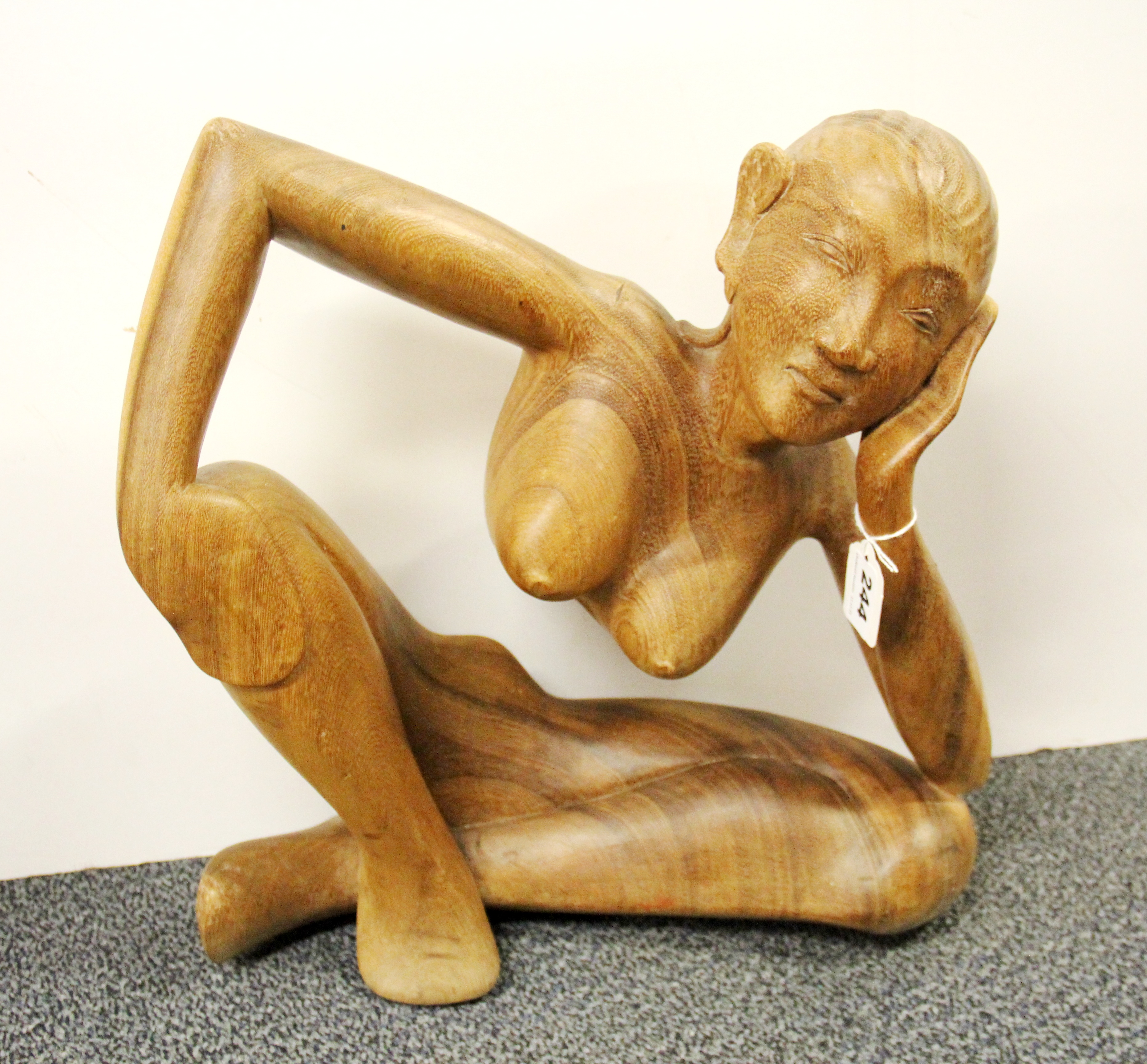 A contemporary Indonesian hardwood sculpture of a nude woman leaning, H. 43cm, W. 40cm.