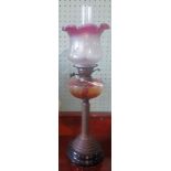 A Victorian oil lamp with cranberry and etched glass shade.