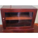 A mahogany single door table top display cabinet.