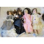 A collection of four smaller porcelain headed dolls in Victorian dress.