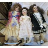 A collection of three porcelain headed dolls in Victorian dress.