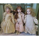 A collection of three porcelain headed dolls in Victorian dress.