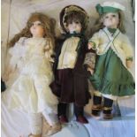 A collection of three porcelain headed dolls in Victorian dress.