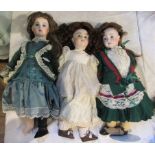 A collection of three porcelain headed dolls in Victorian dress.