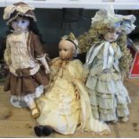 A collection of three porcelain headed dolls in Victorian dress.