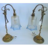 A pair of brass table lamps with blue tinted and etched glass shades.