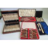A cased horn handled carving set together with a near matching cased set of steak knives and forks,