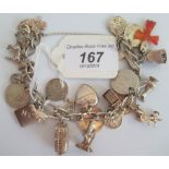 A silver charm bracelet comprising approximately 20 charms to include fire engine, water mill,