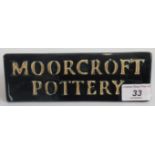 A Moorcroft floral triangular advertising sign, bearing the legend Moorcroft Pottery.