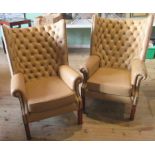 A pair of contemporary wingback fireside chairs with caramel leatherette upholstery.