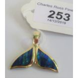 A yellow metal and opal whale tail pendant.