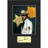Dennis Weaver signature piece mounted below colour photo. Approx overall size 16x11. Good Condition.