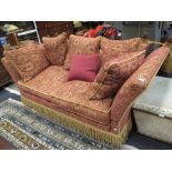 A two seater Knole sofa with pine cone finials upholstered in red and gold fabric with bullion