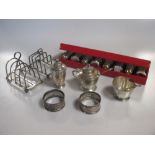 Two silver toast racks, two silver napkin rings, a cased set of eight miniature shakers and a silver