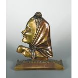 A patinated and gilt bronze female head in profile, cast wearing a head scarf and mounted to a