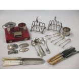 A collection of silver items including toast racks, napkin rings, decanter labels, flatware etc, apx