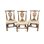 A set of three George III mahogany dining chairs, with pierced and leaf carved vase splat backs