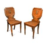 A pair of William IV oak hall chairs, with applied brass armorial crests to the panel backs with