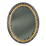 An early 19th century Irish oval mirror, with applied lustre decoration to the ebonised and parcel