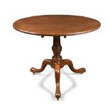 A George III large mahogany tripod table, with a one-piece top, on turned column, pad feet and brass