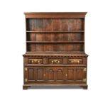 An 18th century oak dresser, with a boarded plate rack and dentil moulded cornice, above a base