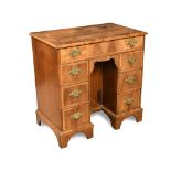 A walnut kneehole desk, the crossbanded top with featherbanded inlay, above one long drawer and