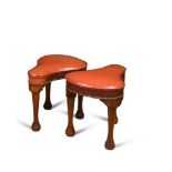 A pair of mahogany framed cockfighting stools, upholstered in brass nailed red leather, on three