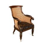 A Regency mahogany library bergere, with curved back, lapit carved arms, leather upholstered arm