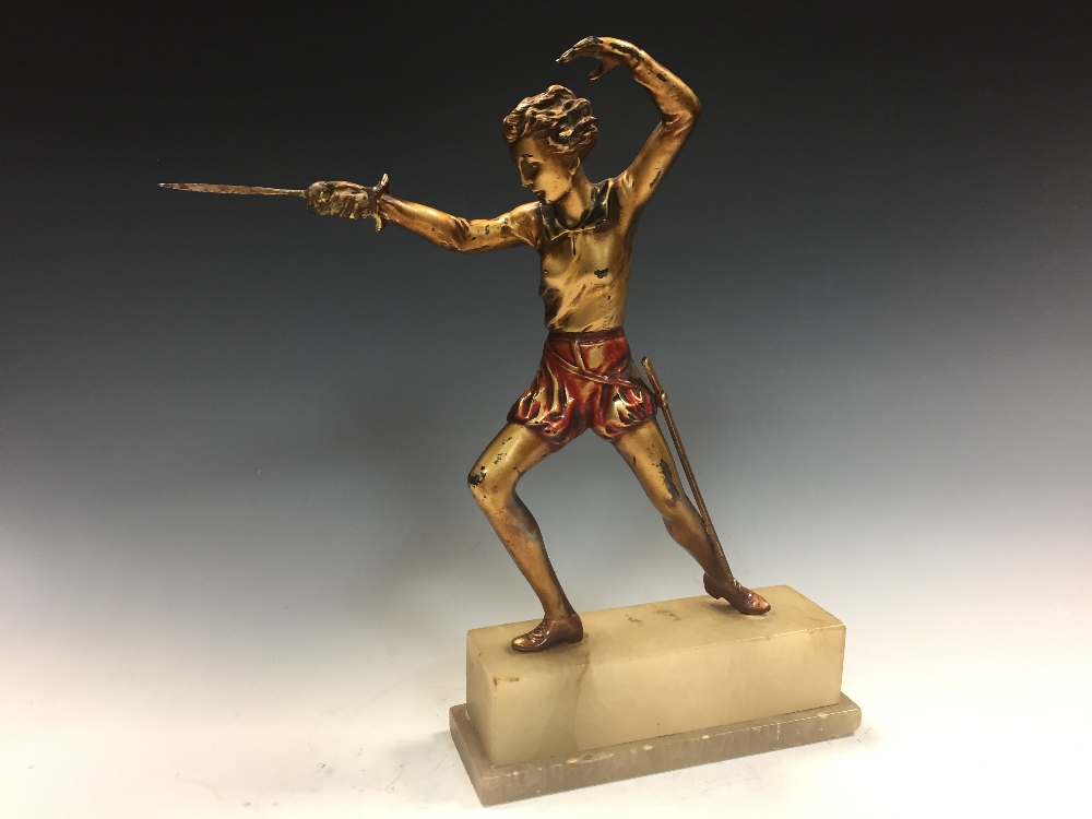 An Art Deco cold painted figure of a female fencer, standing en garde, mounted to an onyx plinth