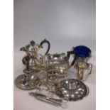 A collection of silver plated items including a teapot, chamberstick, sugar basket with blue glass