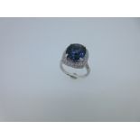 A sapphire and diamond cluster ring, the cushion shaped facetted sapphire with an estimated weight