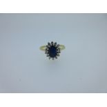 A sapphire and diamond cluster ring, the oval cut sapphire claw set within a border of fourteen