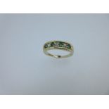 A 9ct gold emerald and diamond half eternity style ring, comprising four round facetted emeralds