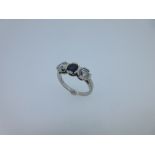 A three stone sapphire and diamond ring set in platinum, the round facetted deep blue sapphire