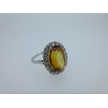 A citrine and diamond cluster ring, the oval cut citrine claw set to a border of round brilliant cut