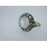 A moonstone and diamond cluster ring, the central round high domed cabochon moonstone surrounded