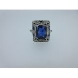 An Art Deco sapphire and diamond ring, the rectangular cushion cut sapphire collet set to a raised