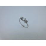 A three stone diamond ring, the graduated round old brilliant cut diamonds claw set with a coronet