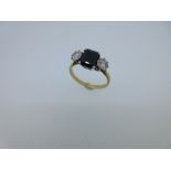 A sapphire and diamond three stone ring, the octagonal cut sapphire between two round brilliant