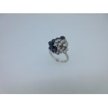An asymmetric diamond, sapphire and 18ct white gold cluster ring, of oval outline with one side