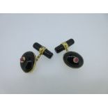 A pair of onyx and ruby cufflinks, each with one end designed as a rub over set high domed oval