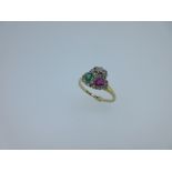 A ruby, emerald and diamond lover's ring, the offset millegrain edged pearshaped emerald and ruby