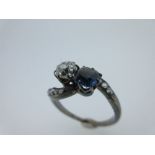 A sapphire and diamond two stone crossover ring, the old cushion cut diamond claw set obliquely to a