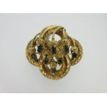 An ornate Victorian knot brooch set with chrysoberyls, the four bold loops of the knot embellished