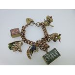 A 9ct gold charm bracelet with quirky and mainly hallmarked charms, the rose gold curb link