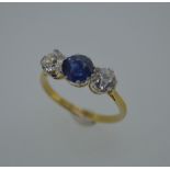 A diamond and sapphire three stone ring, the round cut sapphire claw set between two round brilliant