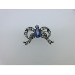 A sapphire and diamond ribbon bow brooch, the central oval cut light blue sapphire beneath an old